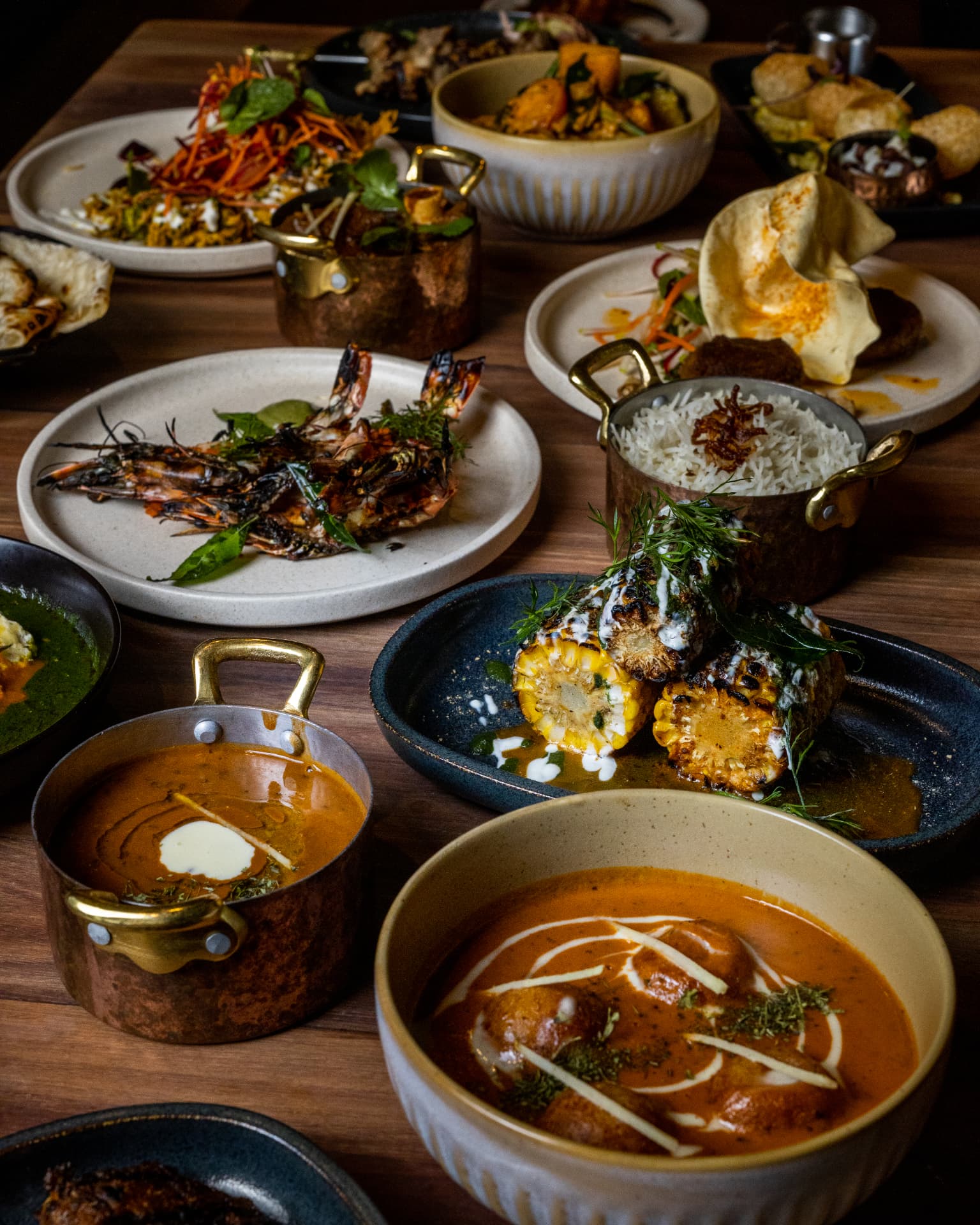 Shared Indian dishes spread across a wooden table