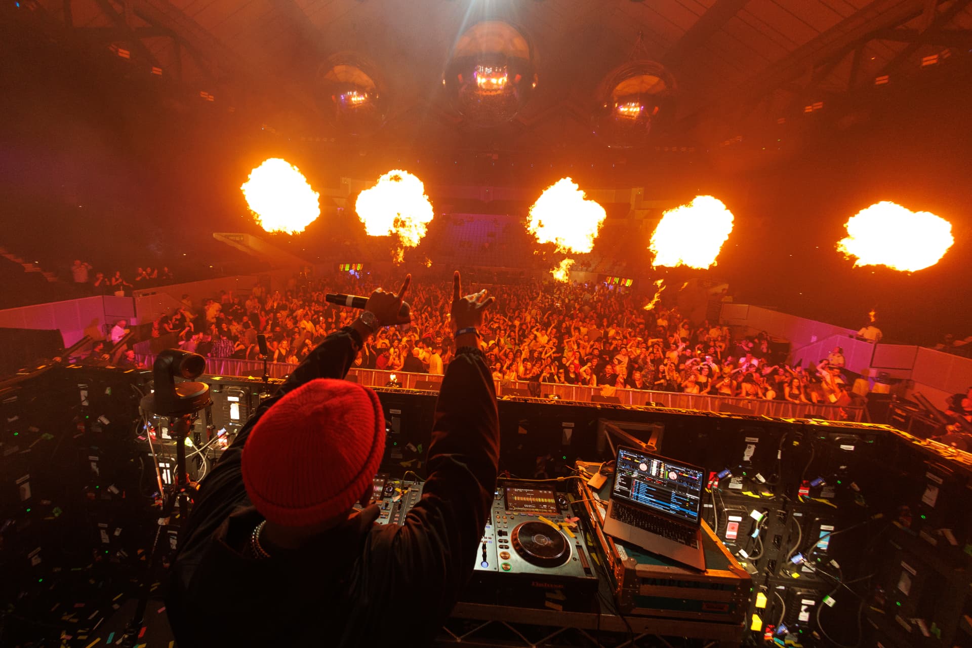 DJ facing a packed arena with flame pyrotechnics at a Chemist Warehouse event