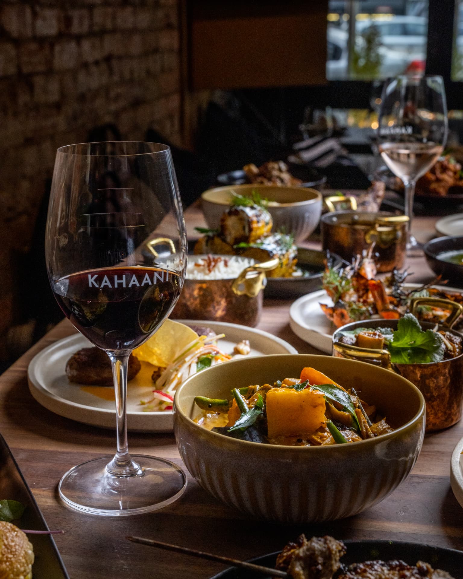 Wine glass and curry dishes at a restaurant table