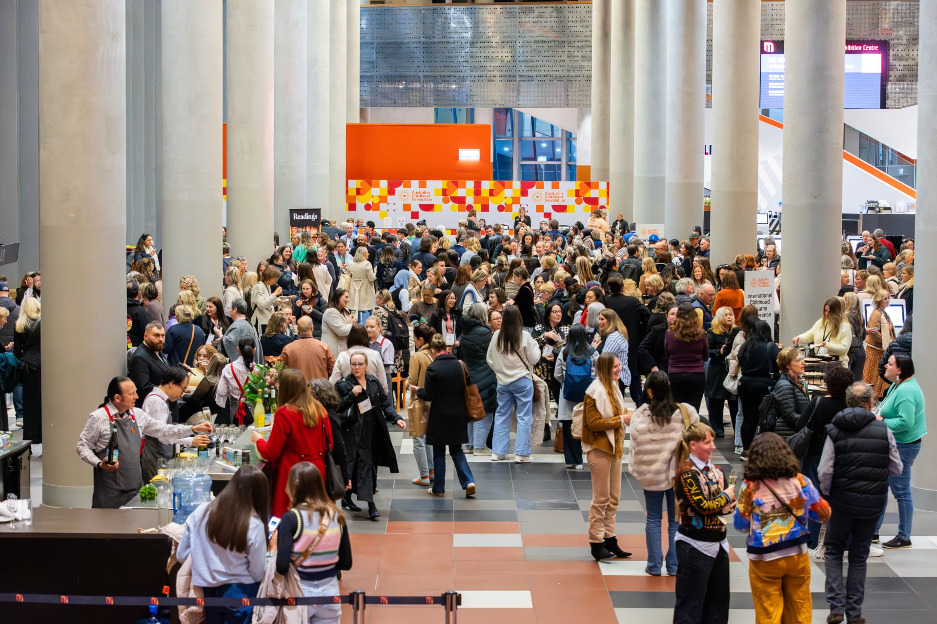 Crowd mingling in the foyer of a conference venue during a networking break