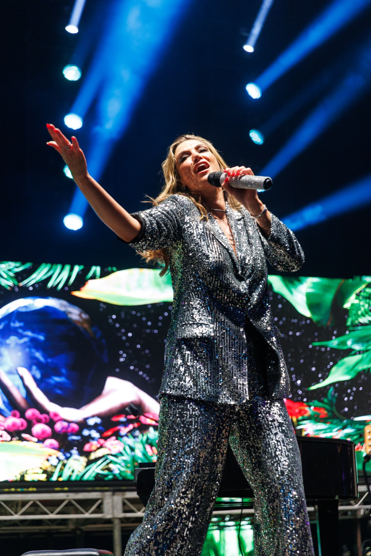 Singer in a sparkling suit performing on stage at a Chemist Warehouse event